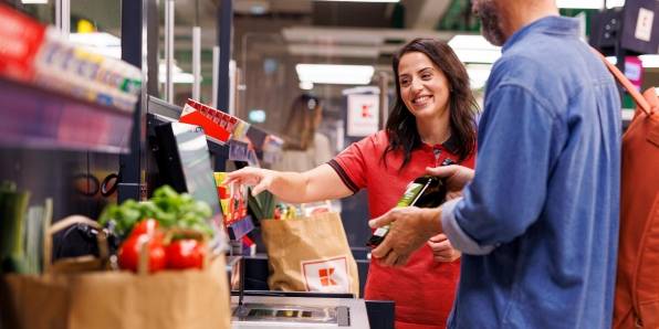 Kaufland-Verkaufsmitarbeiterin hilft einem Kunden an der SB-Kasse.