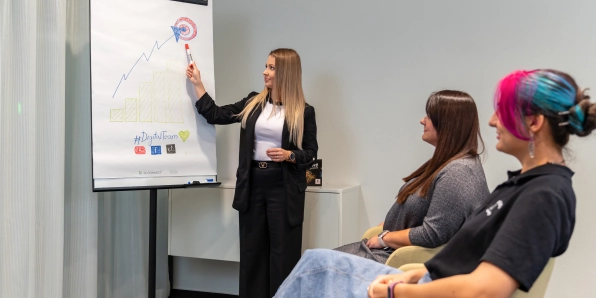 manažérka rozvoja pri nástenke vysvetľuje zamestnancom vývoj grafu