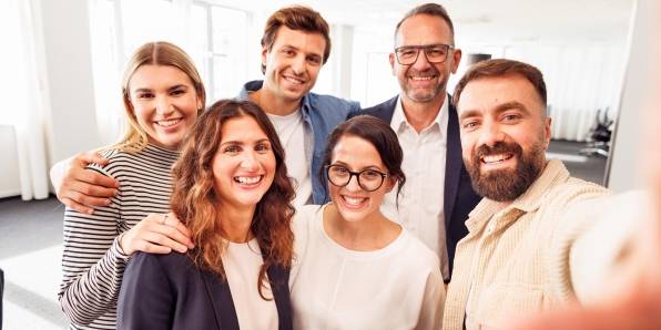 Sechs Kaufland-Mitarbeiter posieren zum Gruppenbild im Büro.