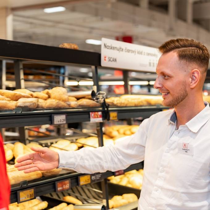manažér ukazuje na vyložené pečivo zamestnancovi pekárne v obchode