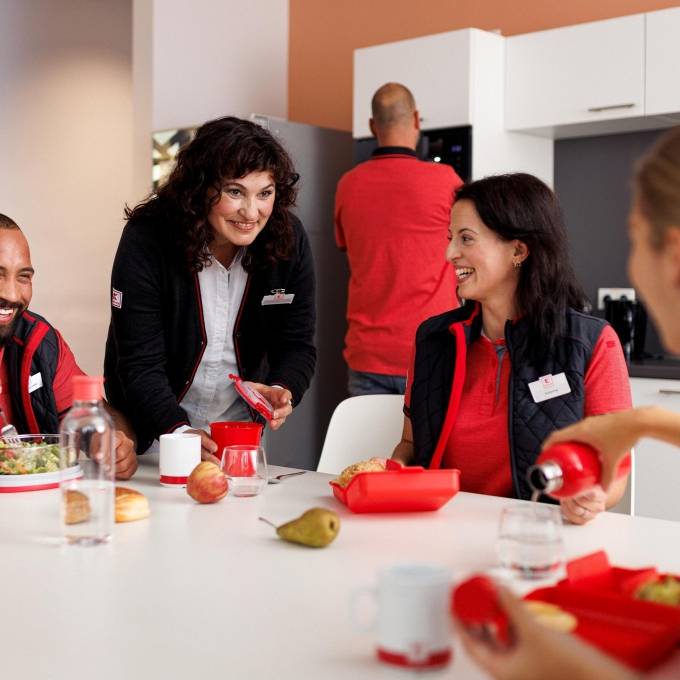 Vier Verkaufsmitarbeiter von Kaufland gut gelaunt bei der Mittagspause im Pausenraum der Filiale.
