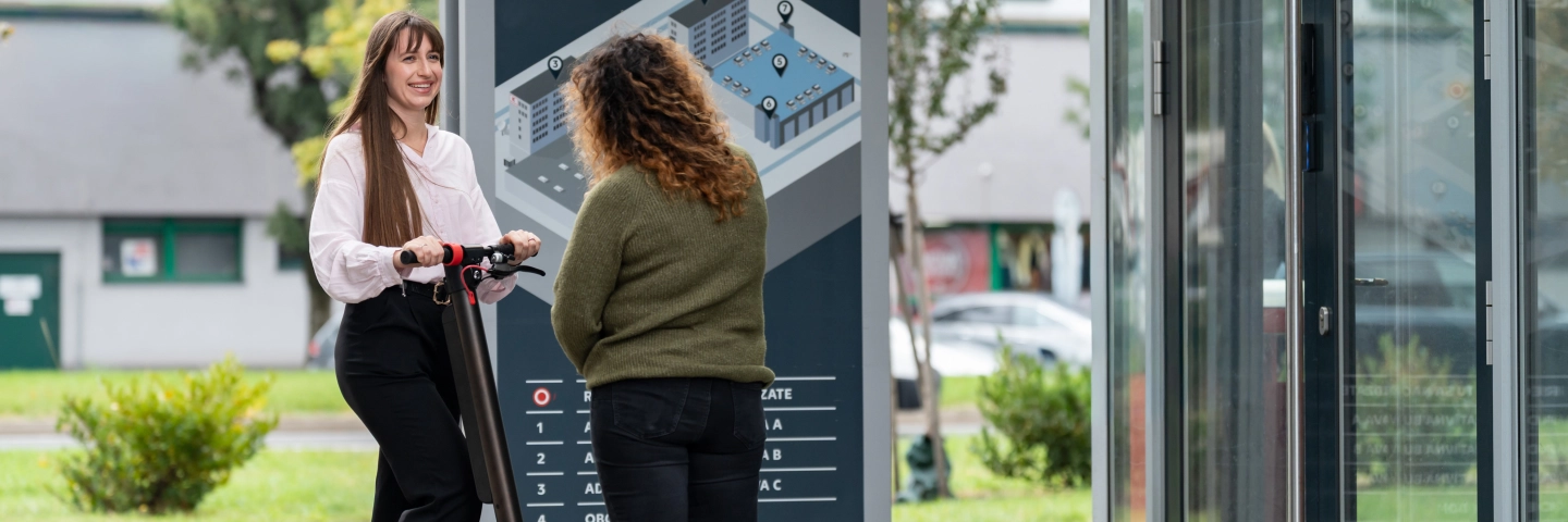 Brigádnička a trainee na kolobežke pred vchodom centrály