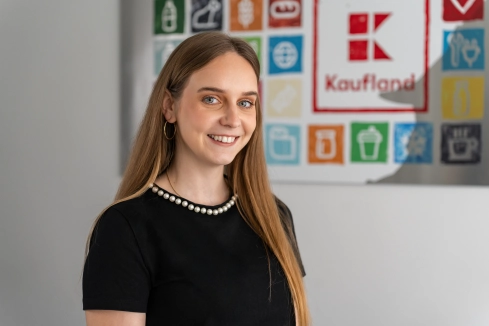 Asistentka z oddelenia nákupu stojí v office pred obrazom Kaufland.