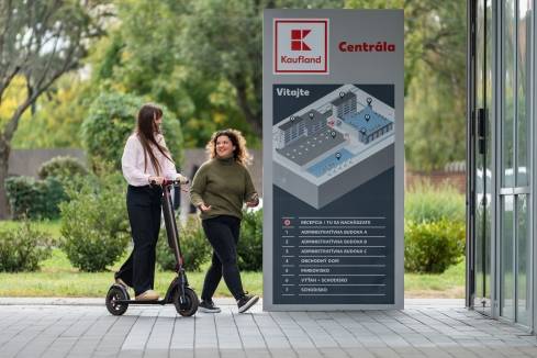 Študentka a brigádnička na kolobežke pred vchodom do centrály