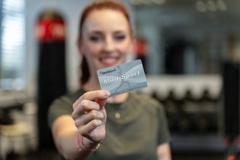 Zamestnankyňa drží kartu Multisport v posilňovni.