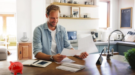 zamestnanec drží doma podklady s bonusmi, na stole má červené prasiatko na šetrenie