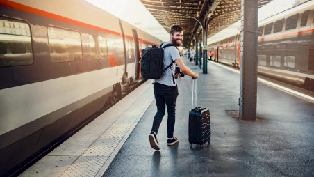 zamestnanec odchádza s kufrom na dovolenku vlakom