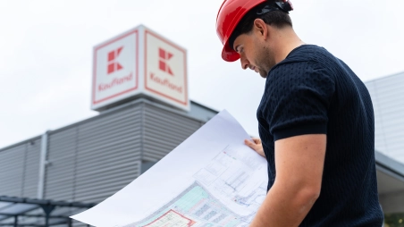 Architekt z oddelenia expanzie číta plán novej predajne pred obchodom