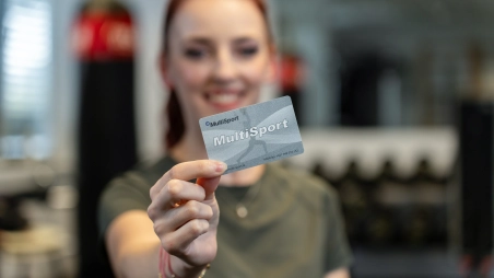 Zamestnankyňa drží kartu Multisport v posilňovni.