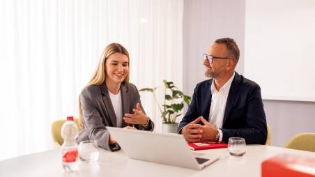 Kandidatin mit Kaufland-Mitarbeiter in einem Konferenzraum der Zentrale beim Bewerbungsgespräch. Auf dem Tisch steht ein aufgeklappter Laptop.
