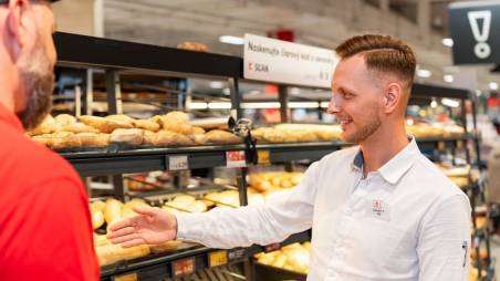 manažér ukazuje na vyložené pečivo zamestnancovi pekárne v obchode