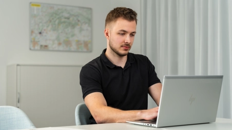 Trainee z oddelenia controllingu v office pracuje na notebooku