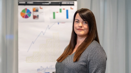 marketingová špecialistka v office pri nástenke s grafom