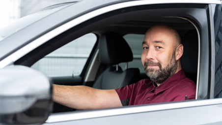 Šofér v aute na parkovisku pozerá z okna auta