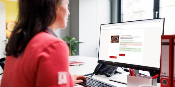 Kaufland-Verkaufsmitarbeiterin am Schreibtisch mit Tastatur und Bildschirm.