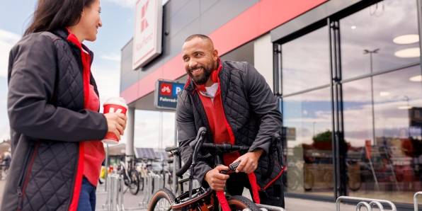 Pause vor der Kaufland-Filiale: Kaufland-Verkaufsmitarbeiter schließt sein Fahrrad an. Neben ihm eine Kollegin mit einem To-Go-Getränk bei der Pause.