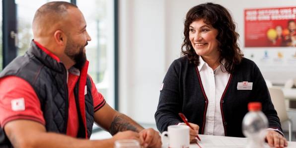 Verkaufsmitarbeiterin von Kaufland unterhält sich mit einem Kollegen im Pausenraum der Filiale.